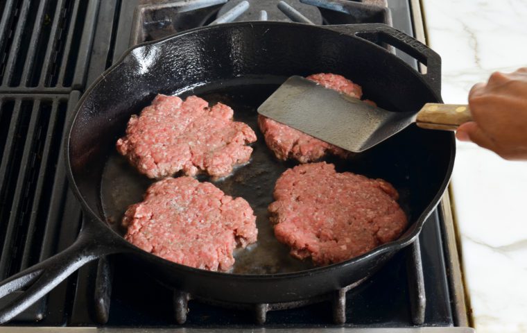 smashing the burgers in the skillet
