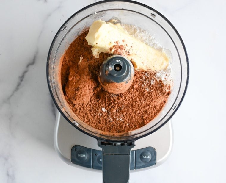 butter, confectioners sugar, and cocoa powder in food processor