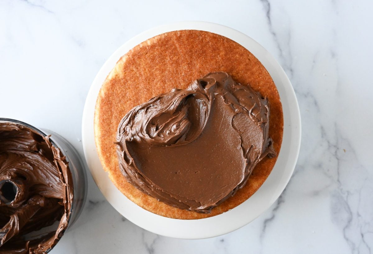 Chocolate buttercream covering half of a yellow cake.