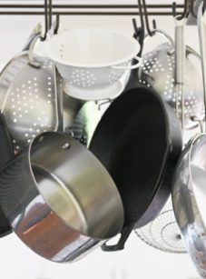 Various pots and pans hanging from a rack.
