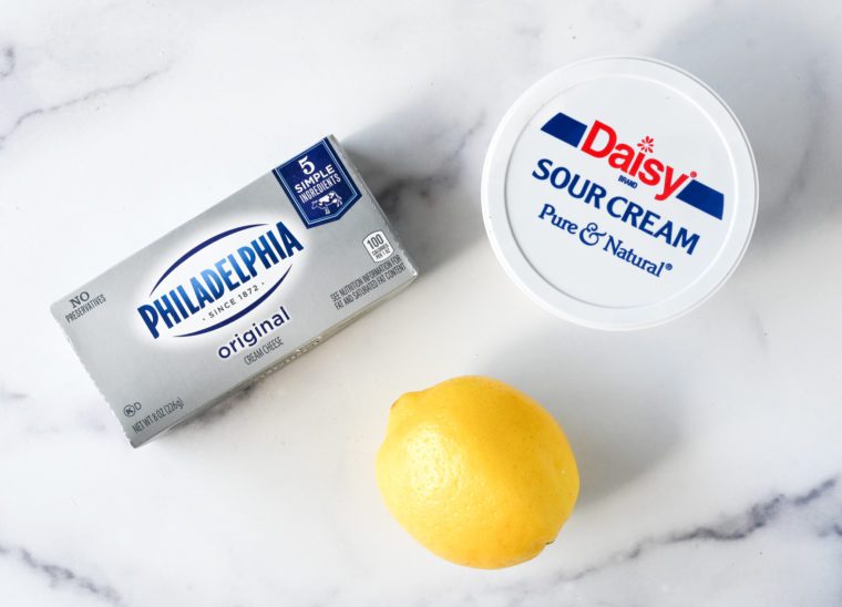 Sour cream, cream cheese, and lemon on a countertop.