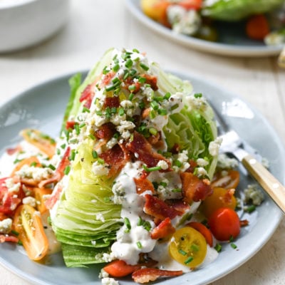 Wedge salad with blue cheese dressing on a plate with a fork.
