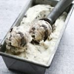 Ice cream scoop in a container of Oreo cheesecake ice cream.