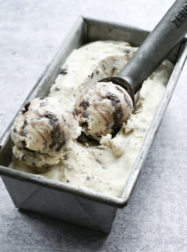 Ice cream scoop in a container of Oreo cheesecake ice cream.
