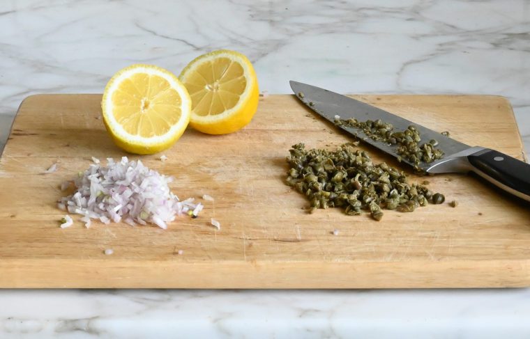 minced shallots, capers, and lemons on cutting board