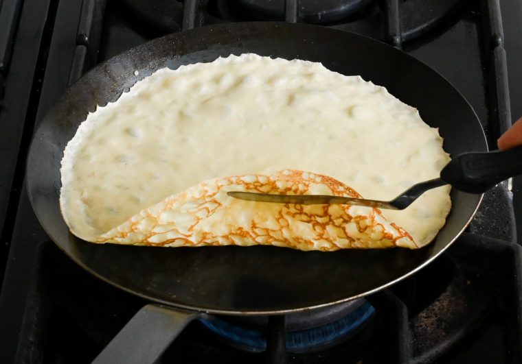lifting the edge of the crepe with an offset spatula