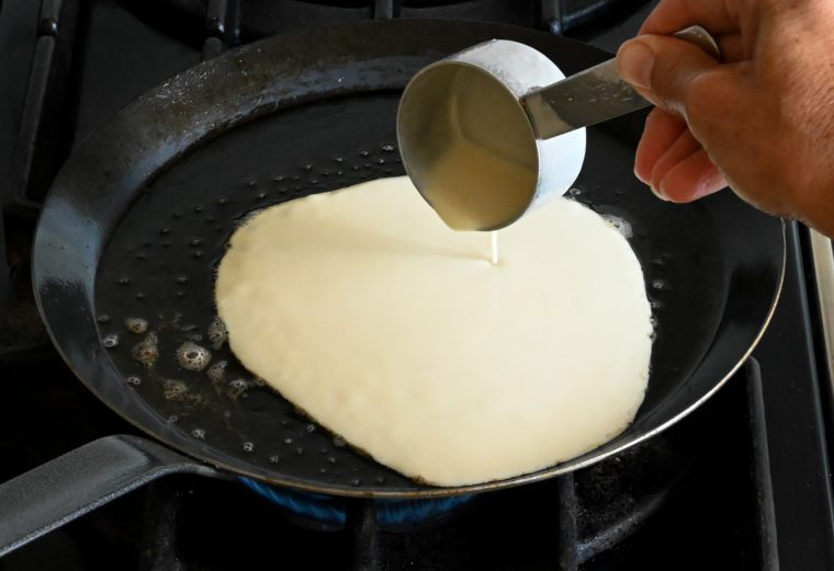 pouring the crepe batter into the pan