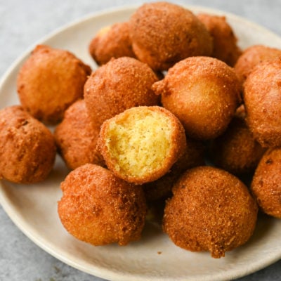 Pile of hush puppies, one of which is missing a bite.