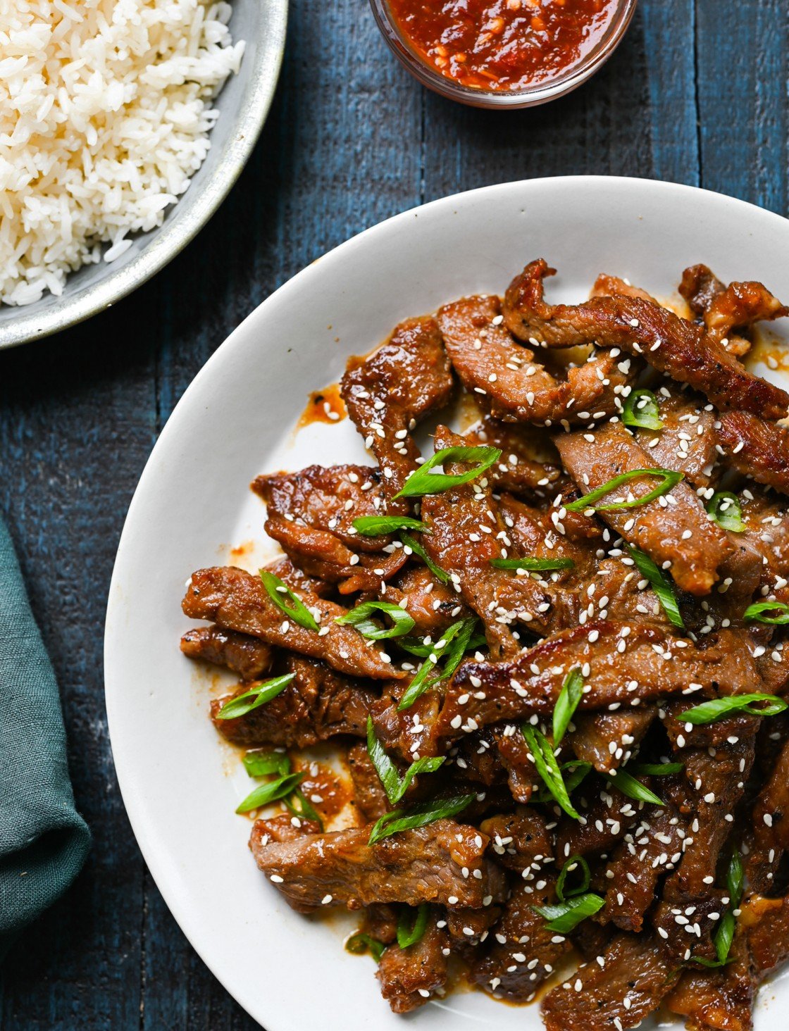Beef bulgogi on platter with rice and hot sauce on the side.