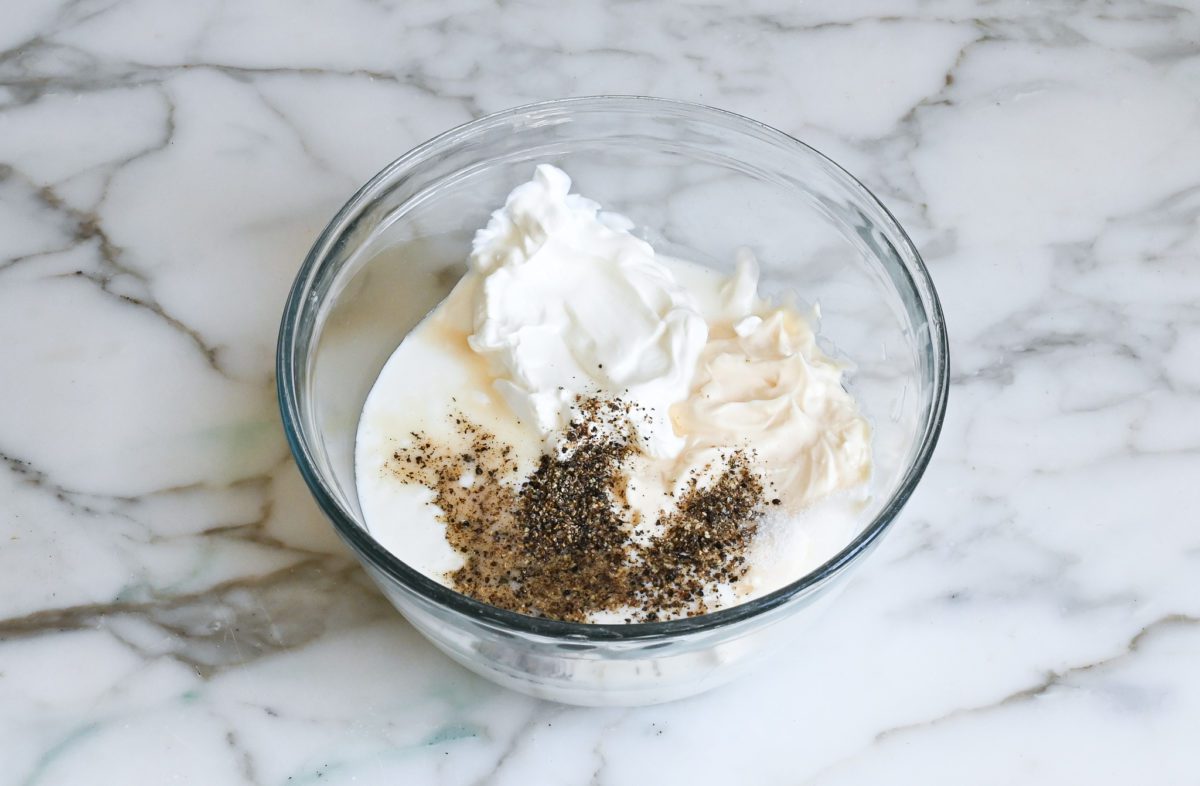 Mayonnaise, sour cream, buttermilk, salt, pepper, garlic, and apple cider vinegar in a bowl.
