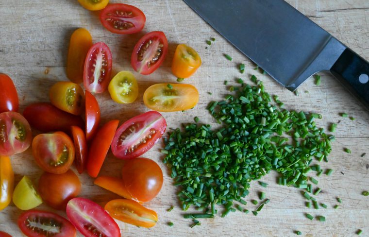 chives and tomatoes on cutting board