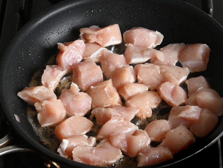 raw chicken pieces in skillet with bacon fat