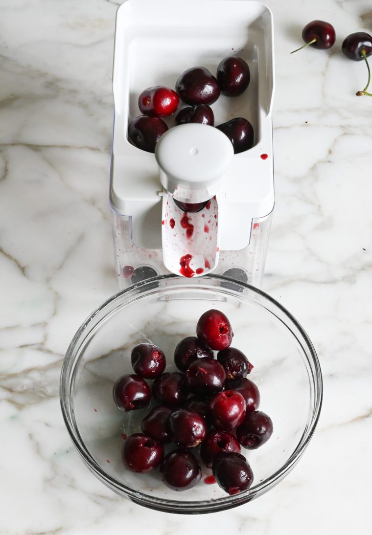 Cherry pitter with a bowl of cherries.