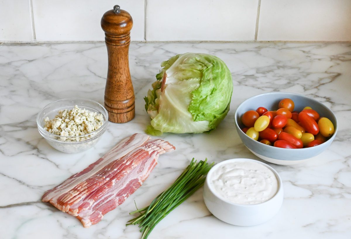 Ingredients to make wedge salad with blue cheese dressing in a bowl on the counter.