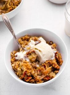 apple crisp in bowl with vanilla ice cream