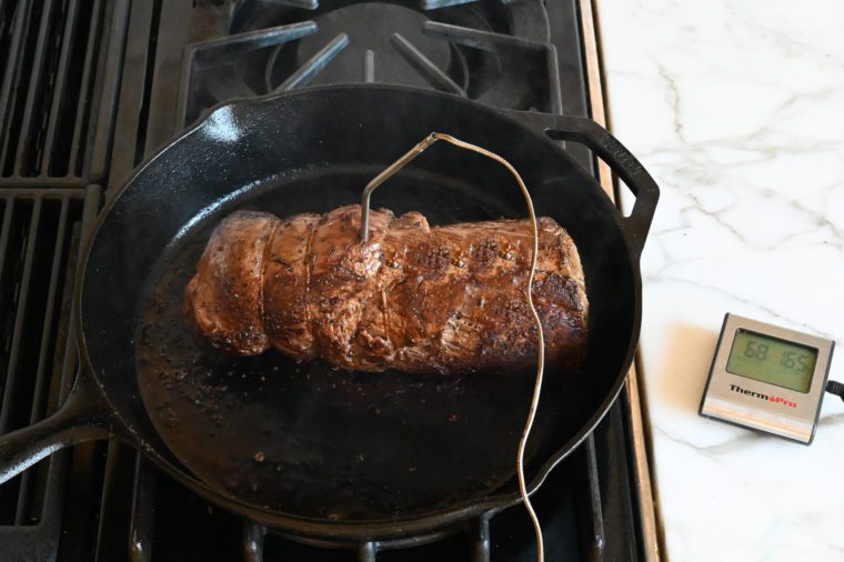 beef tenderloin with leave-in thermometer ready to roast in the oven