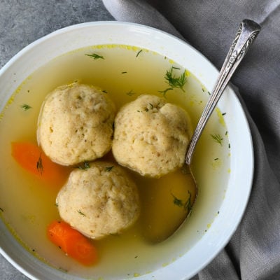 Spoon in a bowl of matzo ball soup.
