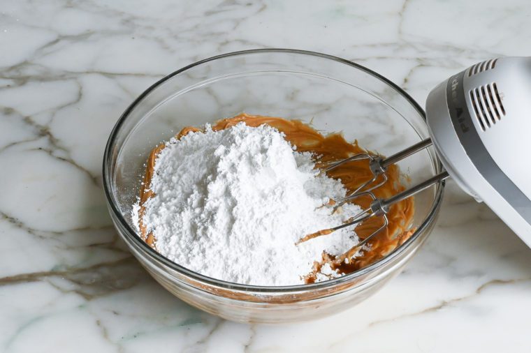 adding confectioners sugar to peanut butter mixture