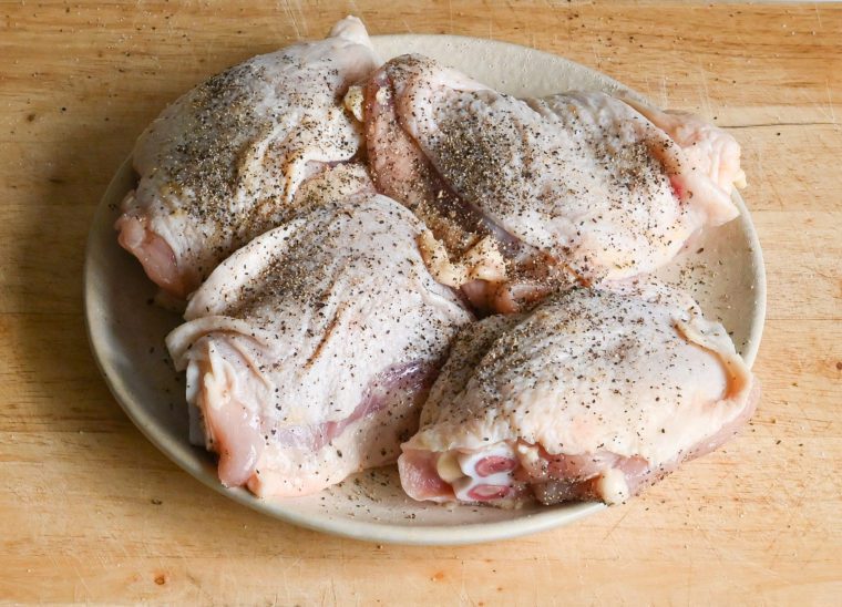 seasoning the chicken with salt and pepper