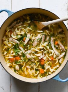 chicken noodle soup in Dutch oven with wooden spoon