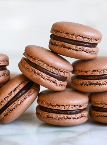 chocolate macarons stacked on white marble