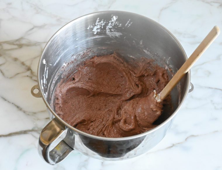 pressing chocolate macaron batter against the bowl 