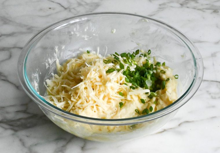 adding cheese and scallions to mashed potatoes