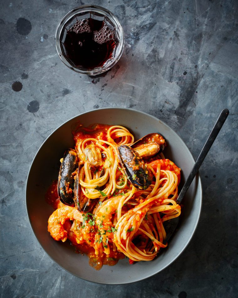 Glass of red wine and a plate of pasta.