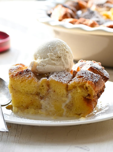 Piece of bread pudding on a plate with a spoon.