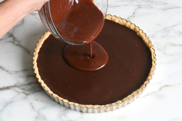 pouring chocolate glaze on chocolate tart