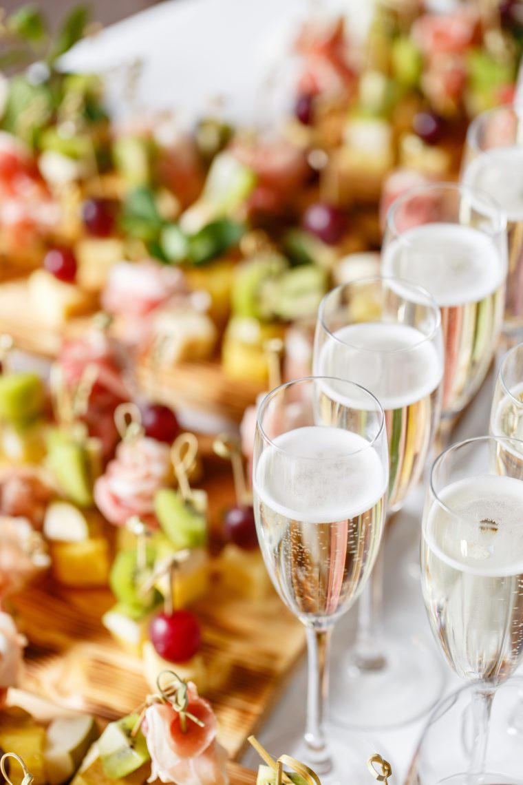 Glasses of sparkling wine on a table with appetizers.