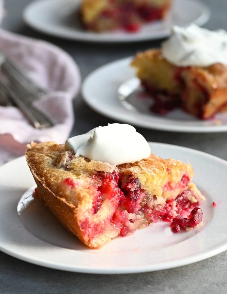 Nantucket cranberry pie on plates with whipped cream.