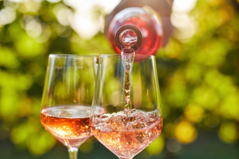 Bottle pouring Rose into a wine glass.