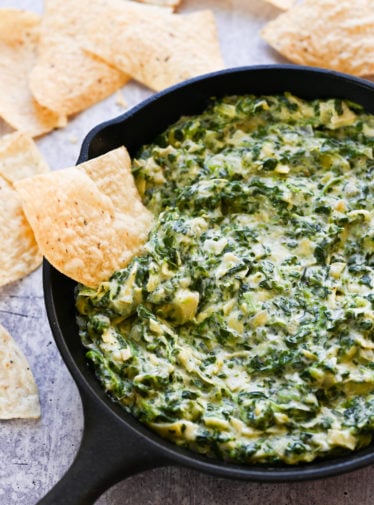 Tortilla chip in a bowl of spinach artichoke dip.