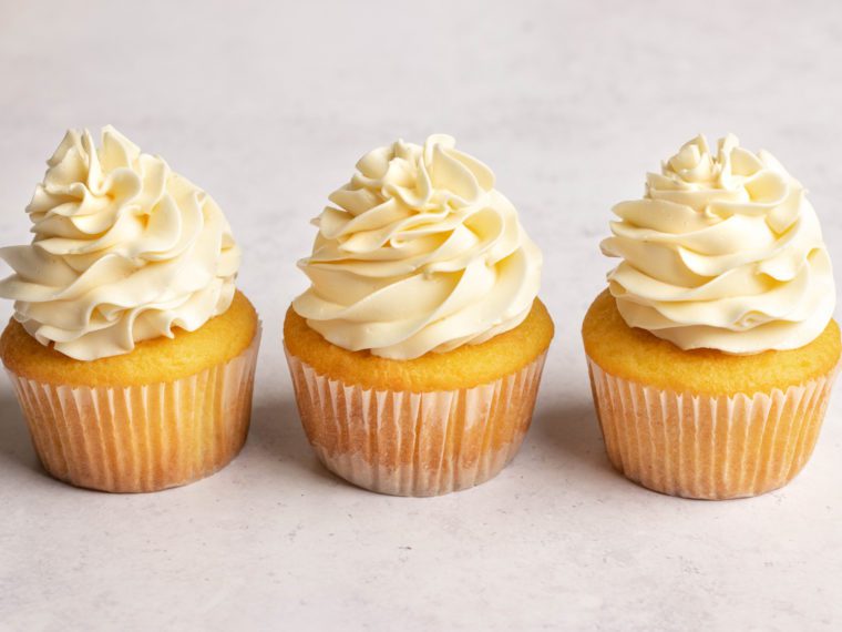 Line of cupcakes topped with Swiss meringue buttercream.