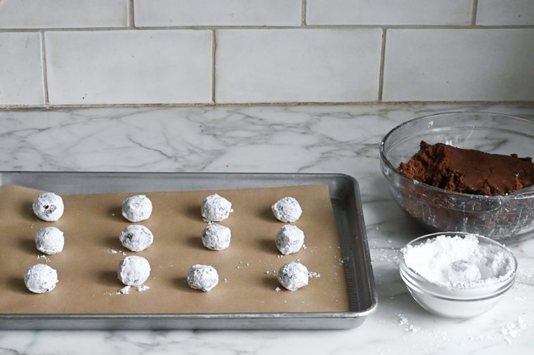 rolling the dough balls in confectioners' sugar