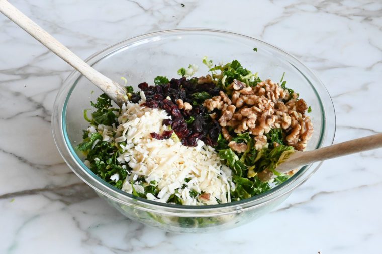 Cheese, cranberries and walnuts added to a bowl of salad.