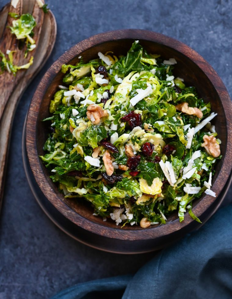 Wooden bowl of kale, brussels sprouts, and dried cranberry salad with honey-dijon vinaigrette.