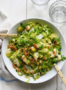 Large bowl of brussels sprout salad with apples, walnuts and parmesan.