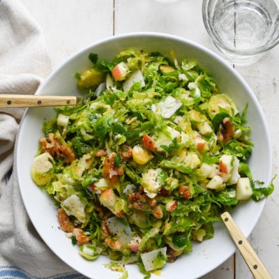 Large bowl of brussels sprout salad with apples, walnuts and parmesan.