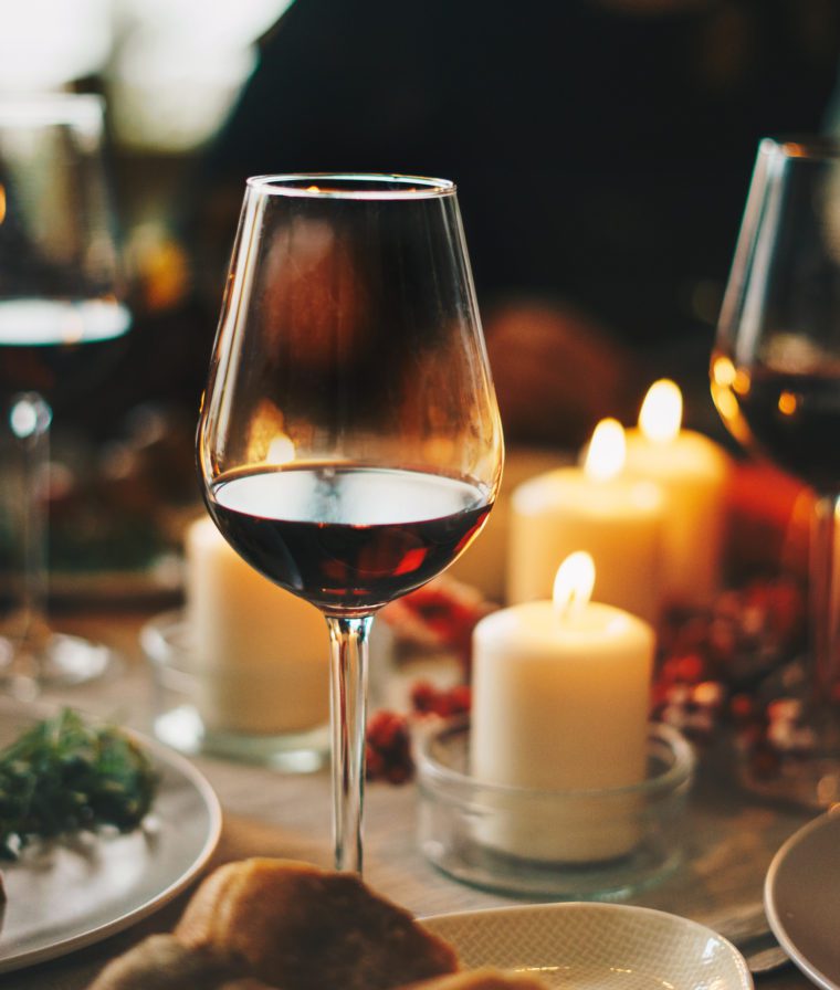 Glasses of zinfandel on a table with lit candles.