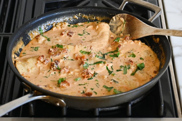 chicken simmering with sauce in skillet