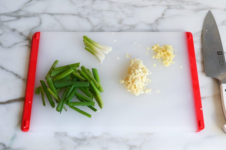 minced garlic and ginger, and sliced scallions on cutting board