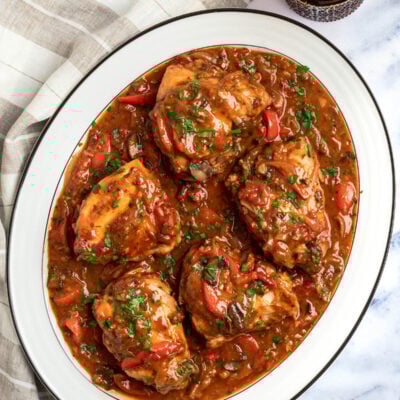 chicken cacciatore on a platter with glass of wine.