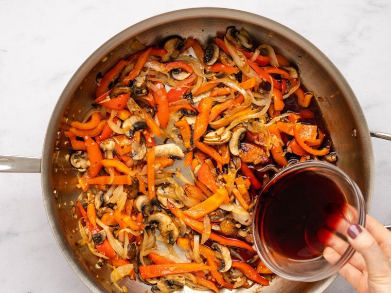 adding red wine to the vegetables in the skillet