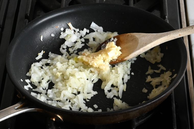 adding the minced garlic to the skillet with the onions