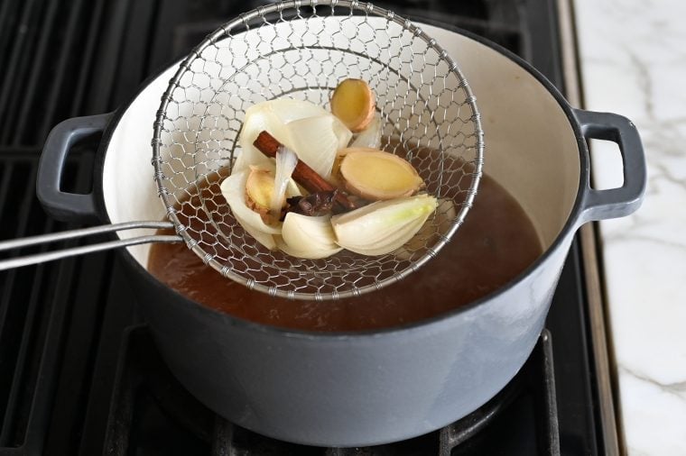 Sieve straining solids out of broth.