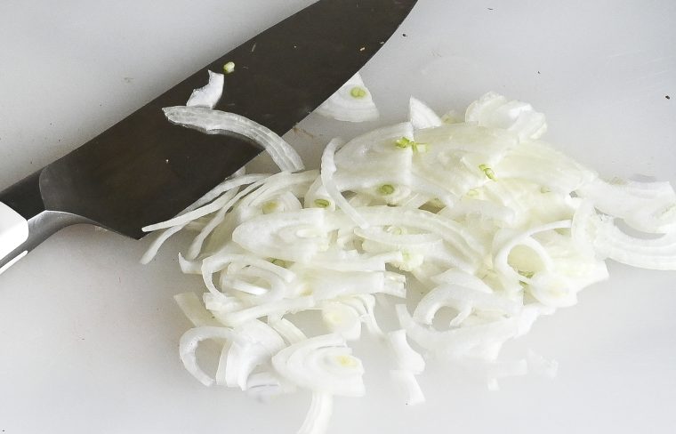 thinly sliced onion on cutting board