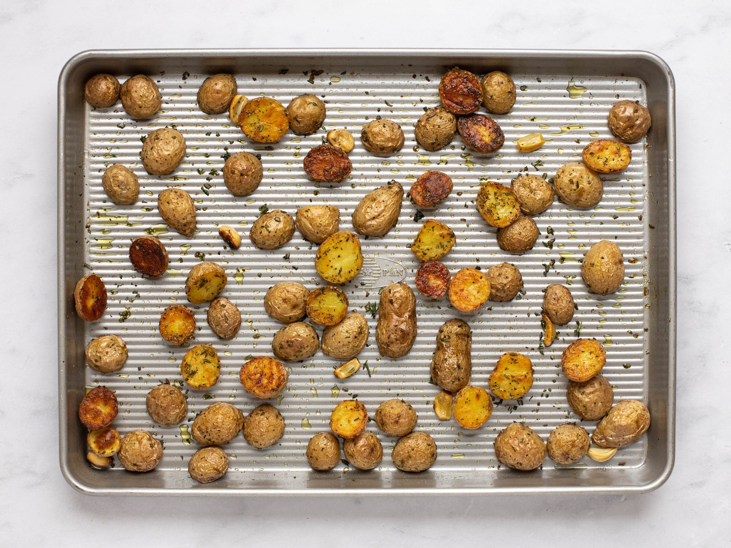 Golden brown roasted potatoes on a baking tray.
