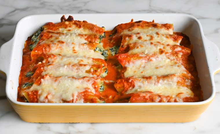 Baked manicotti in a yellow baking dish.